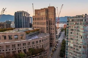 Une vue urbaine avec des bĂątiments modernes, une structure aux lignes courbes et des grues de construction.