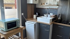 A compact kitchen with a microwave, dishwasher, and a small sink. - Intimate duplex apartment in village center (Bois-le-Roi)
