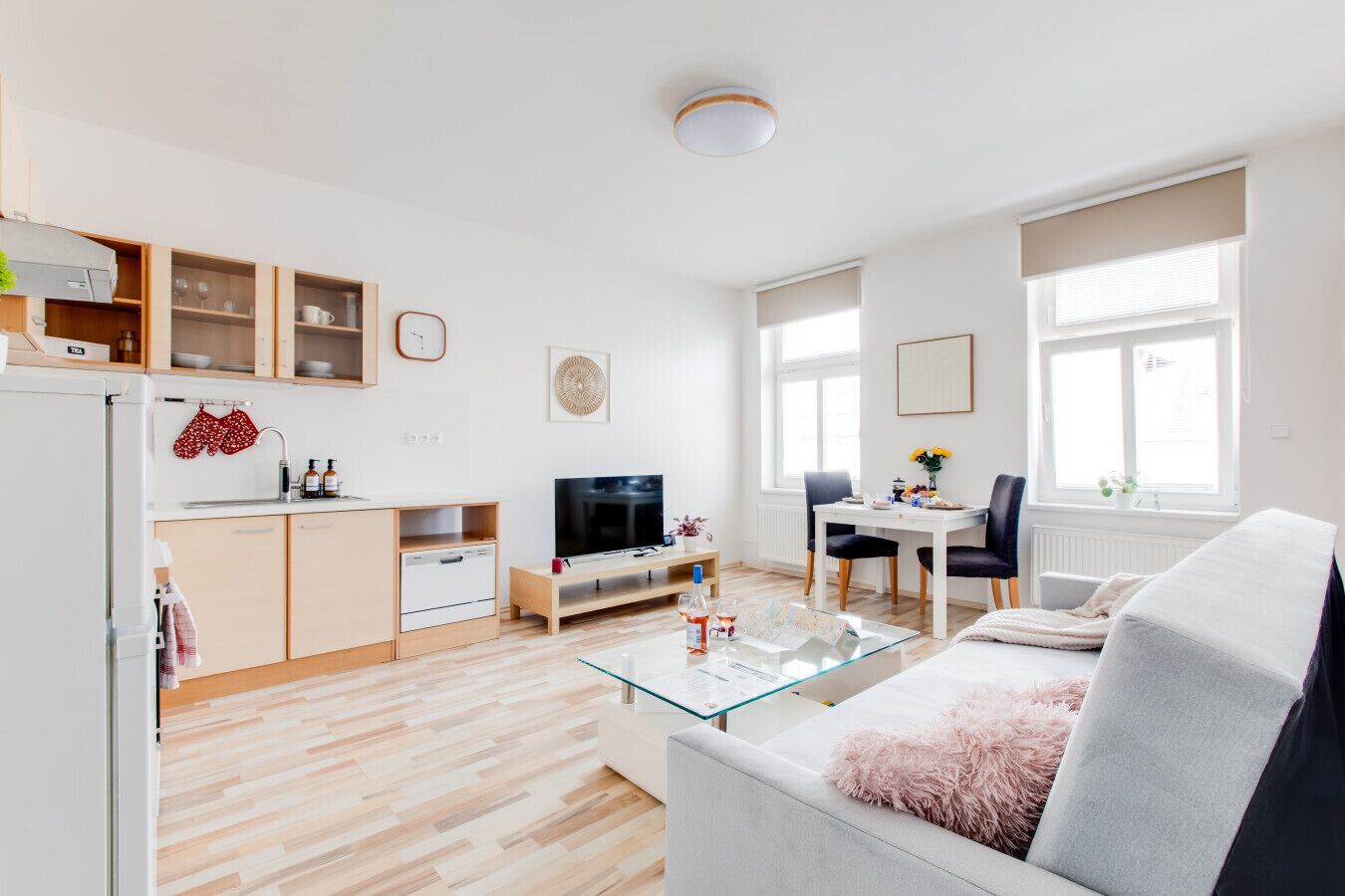 Ein modernes Wohnzimmer mit einer Couch, einem Glastisch, einem Fernseher und einem Essbereich mit Tisch und Stühlen.