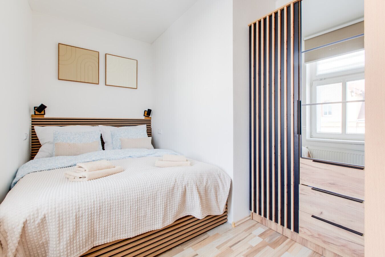 Une chambre à coucher avec un lit, une fenêtre et un panneau de bois vertical.