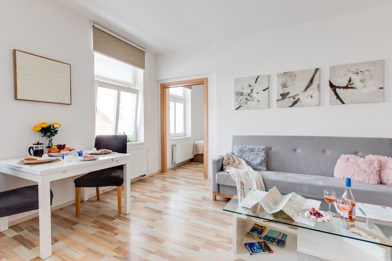 Een moderne woonkamer met een eethoek, een grijze bank en kunst aan de wanden.