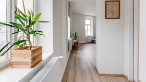Käytävällä on patteri, puulattia, ruukussa oleva kasvi ja seinällä oleva kehystetty taideteos.
