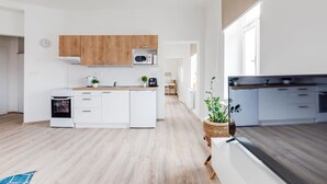 Moderni keittiö, jossa on valkoiset kaapit, puinen työtaso ja mikroaaltouuni.