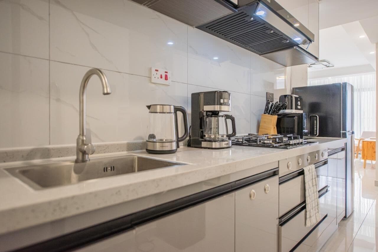 Una cocina moderna con un lavamanos de acero inoxidable, una cafetera, una estufa y un refrigerador.