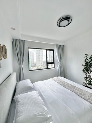 Una habitación de hotel con cama, una ventana con cortinas, una lámpara en el techo y una planta.