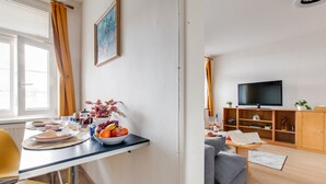 Kompakti oleskelutila, jossa on ruokailualue, sohva, televisio ja pieni kaappi.