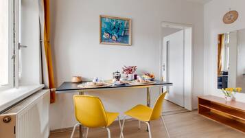 En matplats med ett bord dukat för två personer, en tavla på väggen och en spegel ovanför bordet.