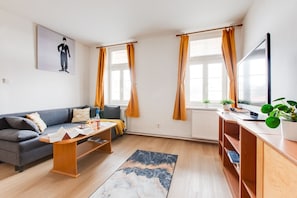 Un salon moderne avec un canapé, une table basse et un téléviseur posé sur un meuble en bois.