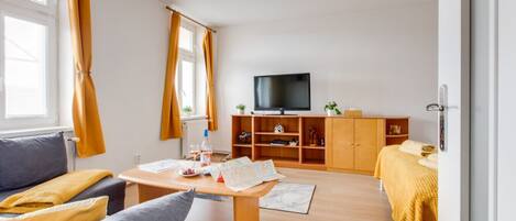 A modern living room with a sofa, a coffee table, a TV, and a wooden cabinet.
