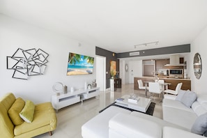 A modern living room with a sofa, coffee table, and a painting of a beach scene.