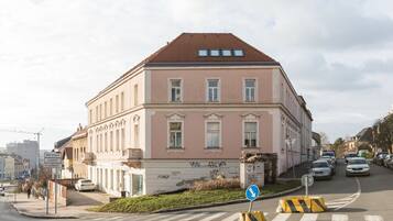 A pink building with a tiled roof, a pedestrian crossing, and a blue directional sign.