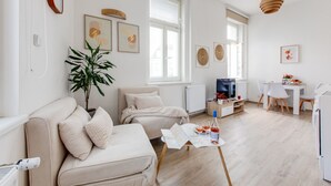 Un salon moderne avec un canapé, une table à manger, un téléviseur et une grande plante.