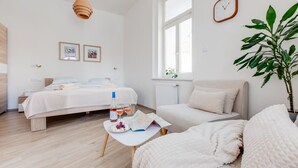Une chambre moderne avec un lit, une table de chevet et un coin lecture comprenant un fauteuil et une plante.