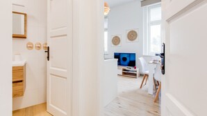 Un appartement moderne avec un plancher en bois, des murs blancs, une télévision et un coin repas.