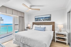 Ein Hotelzimmer mit einem großen Bett, einem Deckenventilator, Blick aufs Meer und einem Balkon.