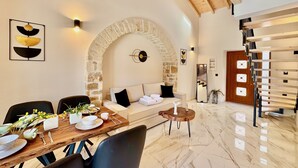 Ein modernes Interieur mit einem Steinbogen, einer Holztreppe und einem Essbereich mit Marmorboden.
