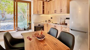 Una cocina moderna con armarios de madera, un refrigerador de acero inoxidable y una mesa de comedor con sillas.