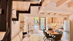 Una cocina moderna con armarios de madera, un comedor con mesa y sillas, y una escalera que lleva a un nivel superior.