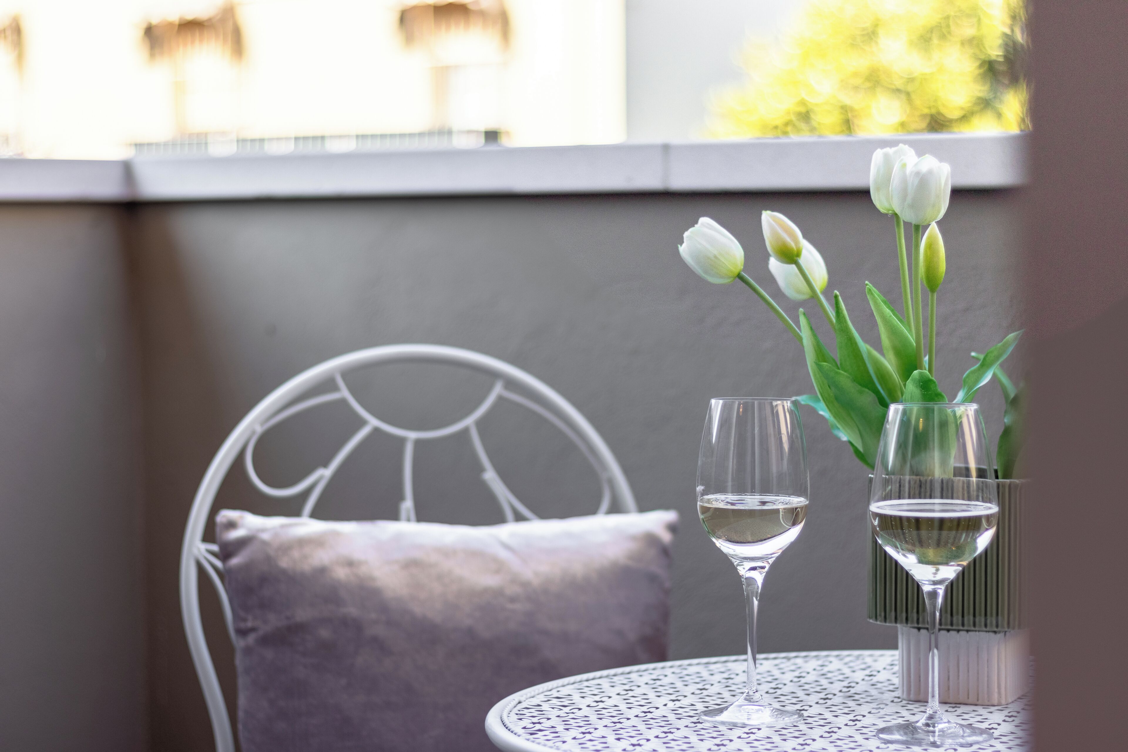 Ein runder Tisch mit zwei Weingläsern und einer Vase mit weißen Blumen.