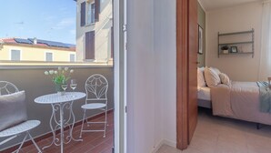 A balcony with a table and chairs, a bed, and a door leading to another room. - Green Botanical House with Free Parking (San Giorgio di Piano)