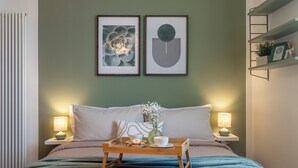 A neatly made bed with a tray of breakfast items, two bedside lamps, and framed artwork on the wall. - Green Botanical House with Free Parking (San Giorgio di Piano)