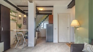 A modern kitchen with a dining area, a staircase, and a living room with a sofa and lamp. - Green Botanical House with Free Parking (San Giorgio di Piano)
