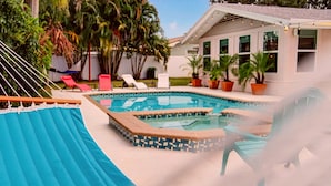 A swimming pool with a tiled deck, lounge chairs, and potted plants. - Tropical Home: Private Pool, Near Clearwater Beach (Clearwater)