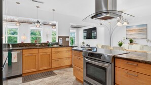 A modern kitchen with wooden cabinets, stainless steel appliances, and pendant lighting. - Tropical Home: Private Pool, Near Clearwater Beach (Clearwater)
