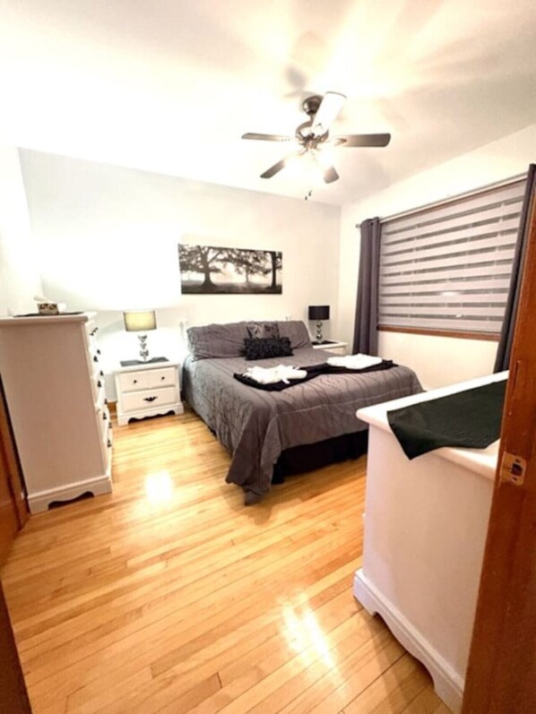 A bedroom with a bed, bedside table, lamp, and a ceiling fan.
