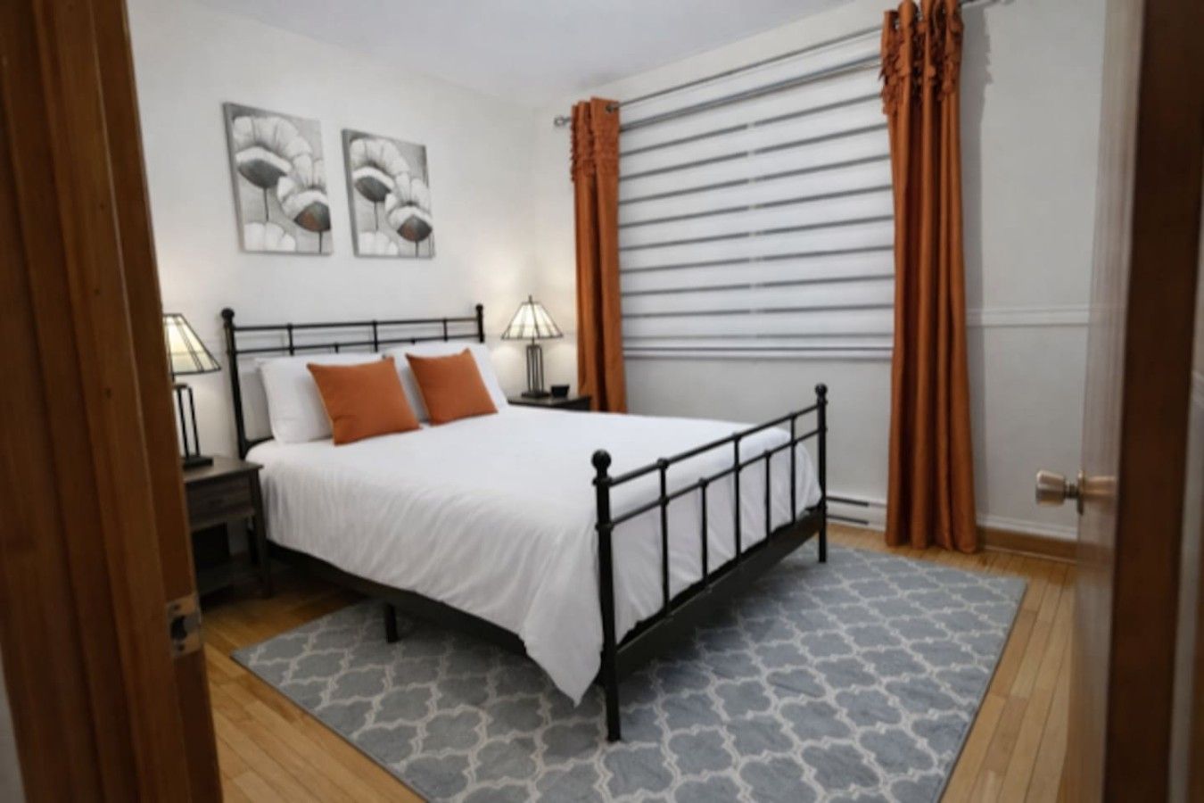 A bedroom with a bed, nightstands, a lamp, and a window with curtains.