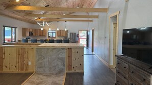Una cucina moderna con travi in legno, un'isola centrale e un grande televisore.