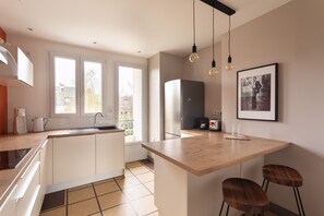 A modern kitchen with a central island, a refrigerator, and a coffee machine. - Ty Thabor - Avec Parking Privé (Rennes)