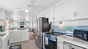 A modern kitchen with white cabinetry, stainless steel appliances, and a central island. - Mini Golf Heated Pool Ocean Front Family Fun (Holden Beach)