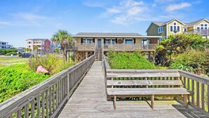 A wooden boardwalk leading to a beachfront property with multiple levels and a bench. - Mini Golf Heated Pool Ocean Front Family Fun (Holden Beach)