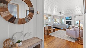 A room with a round mirror, wooden fish decorations, a white wall, a wooden floor, a sofa, a table, and a lamp. - Mini Golf Heated Pool Ocean Front Family Fun (Holden Beach)