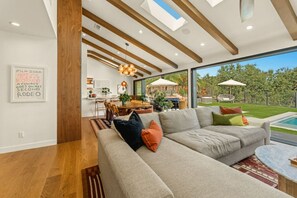 A modern living room with a large sofa, a dining area, and a view of the outdoors. - Modern Luxury Retreat w/ Pool Spa & Stunning Views (Los Angeles)