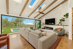 A modern living room with a large sofa, a TV, and a fireplace. - Modern Luxury Retreat w/ Pool Spa & Stunning Views (Los Angeles)
