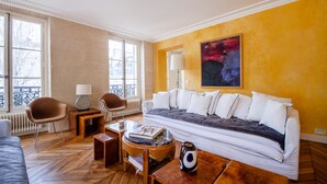 A living room with a sofa, chairs, a coffee table, and a lamp.