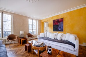 A living room with a sofa, chairs, a coffee table, and a lamp. - Saint Germain Artiste (Paris)
