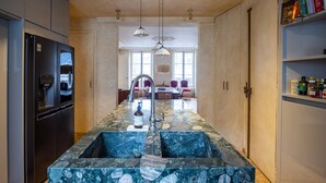 A kitchen with a central island, a refrigerator, and a dining area with chairs and a table.