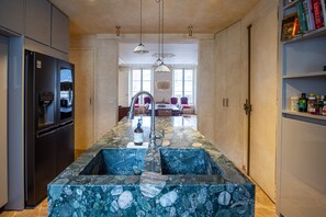 A kitchen with a central island, a refrigerator, and a dining area with chairs and a table. - Saint Germain Artiste (Paris)