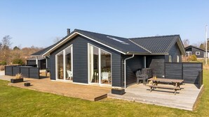 Ein modernes Haus mit einer großen Terrasse, einer überdachten Veranda und einem Swimmingpool.