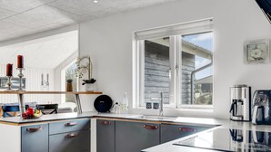 Eine moderne Küche mit einer großen Kochinsel, eingebauten Geräten und einem Fenster, das natürliches Licht hereinlässt.