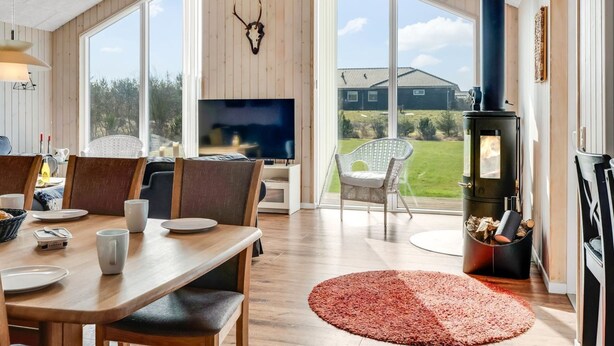 Ein geräumiger Wohnbereich mit großem Fernseher, Holzboden und Kamin aus Stein.