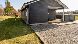 Ein modernes Gebäude mit überdachter Terrasse, einem Schotterweg und einem Rasen.