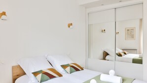Een hotelkamer met een bed, nachtkastje, spiegel en een wandlamp.