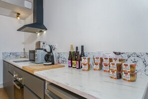Eine moderne Küche mit Marmorarbeitsplatte, einem Toaster, einer Mikrowelle, einem Holzer Schneidebrett und verschiedenen Lebensmitteln.