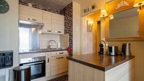 A modern kitchen with stainless steel appliances, wooden cabinets, and a built-in oven. - Les Essarts Marine - Au bord de la plage (Courseulles-sur-Mer)