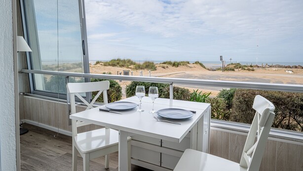 A balcony with a table set for two, overlooking a beach. - Les Essarts Marine - Au bord de la plage (Courseulles-sur-Mer)
