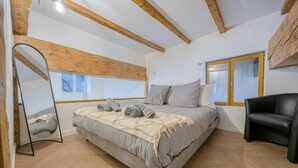 Un dormitorio con cama, espejo, ventana y techo de madera.